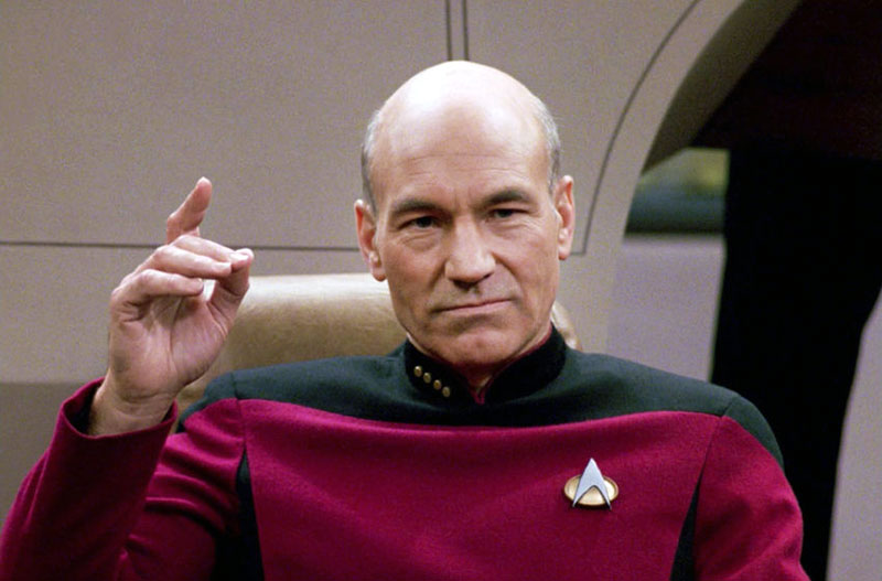 Patrick Stewart as Capt. Picard wearing a Combadge on TNG